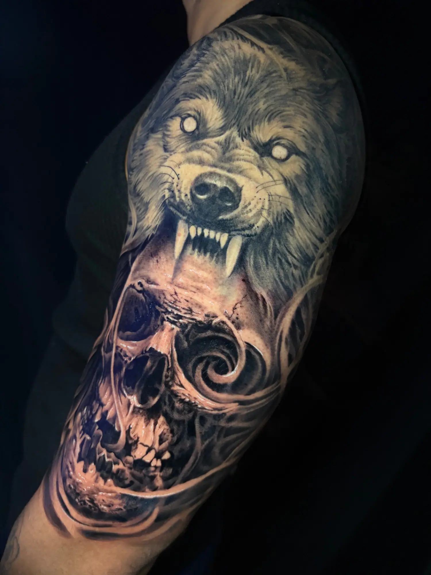 Tatuagem de lobo sobre caveira em realismo preto e cinza, feita no Gautama